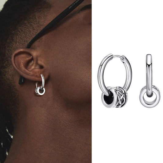Silver hoop earrings worn on an ear with a close-up of the earring design.