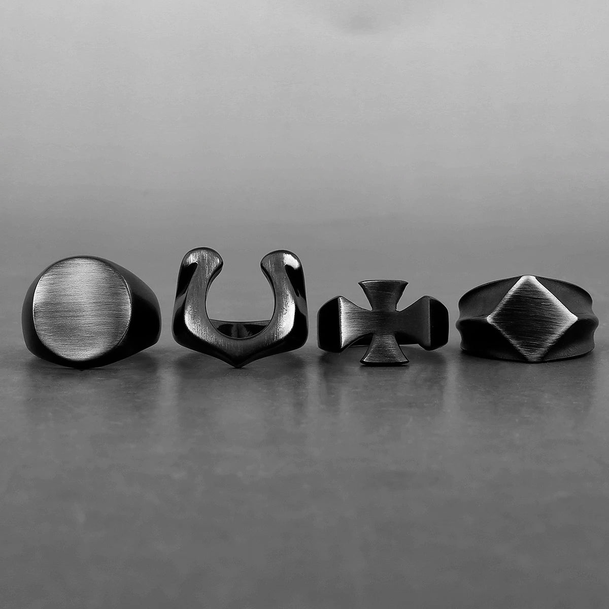 Set of four black stainless steel rings with unique Viking designs displayed in a row.