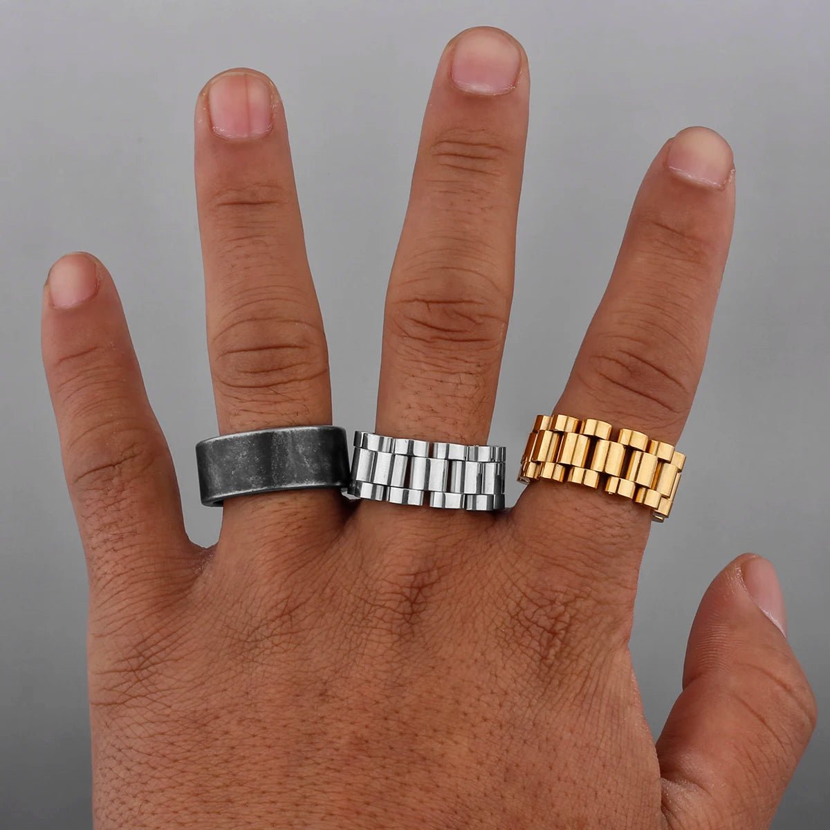 Hand wearing three Nordic Viking stainless steel rings in silver, gold, and matte black.