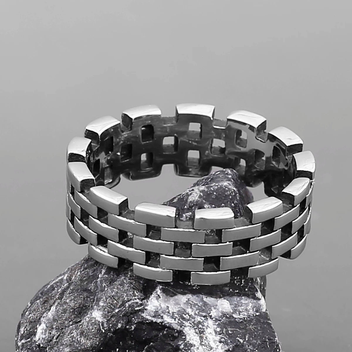 Polished silver stainless steel woven Viking ring displayed on a rock.