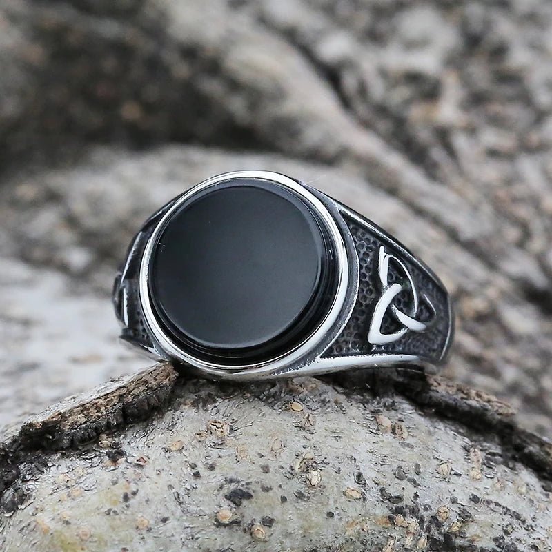 The Trinity of Power Ring with a polished black stone, showcasing the engraved Trinity Knot symbols on the sides.