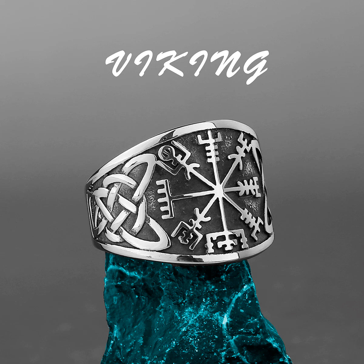 Stainless steel Viking ring featuring the Vegvisir symbol and Celtic knot engravings, set on a rugged blue stone background.