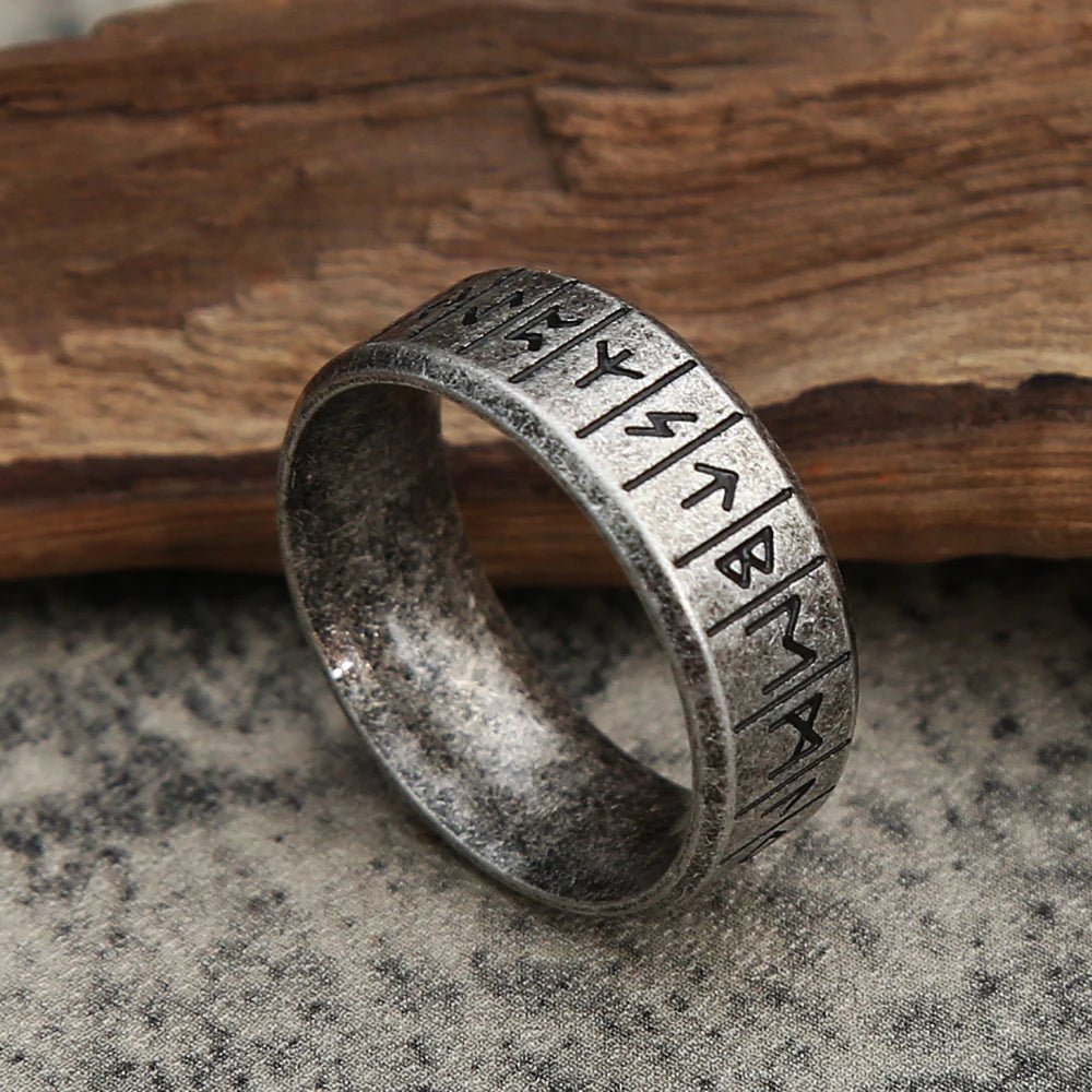 Viking Rune Ring angled side view with detailed Norse rune engravings, placed on a wooden background.