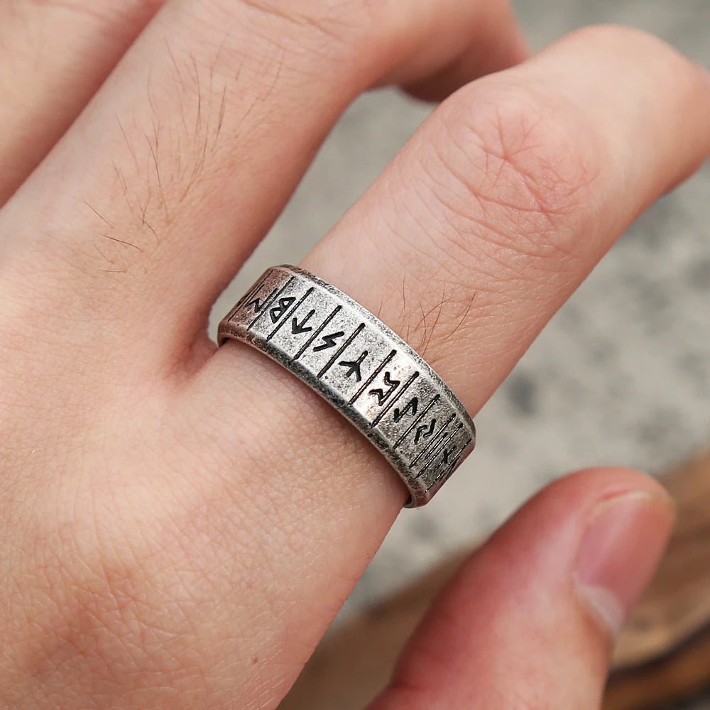 Viking Rune Ring close-up with Norse runes, placed on a wooden background.